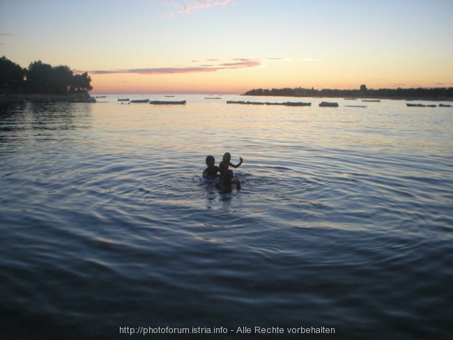 Kinder baden Abends in einer Bucht in Valalta